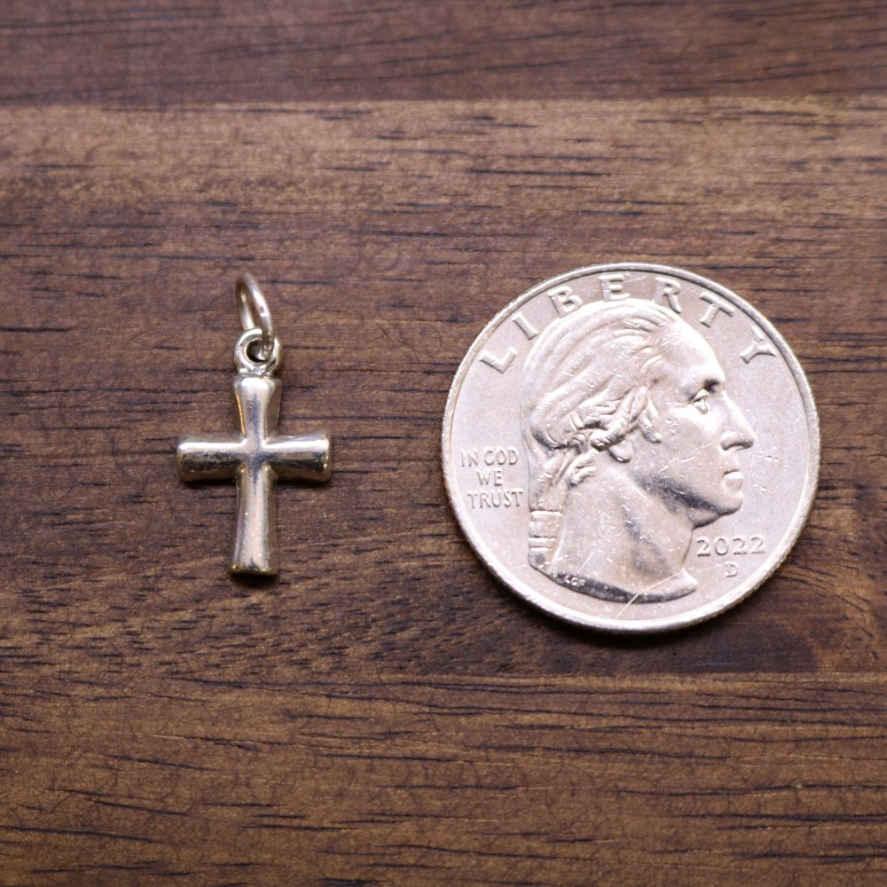 Sterling silver cross charm pendant next to a US quarter for size comparison.