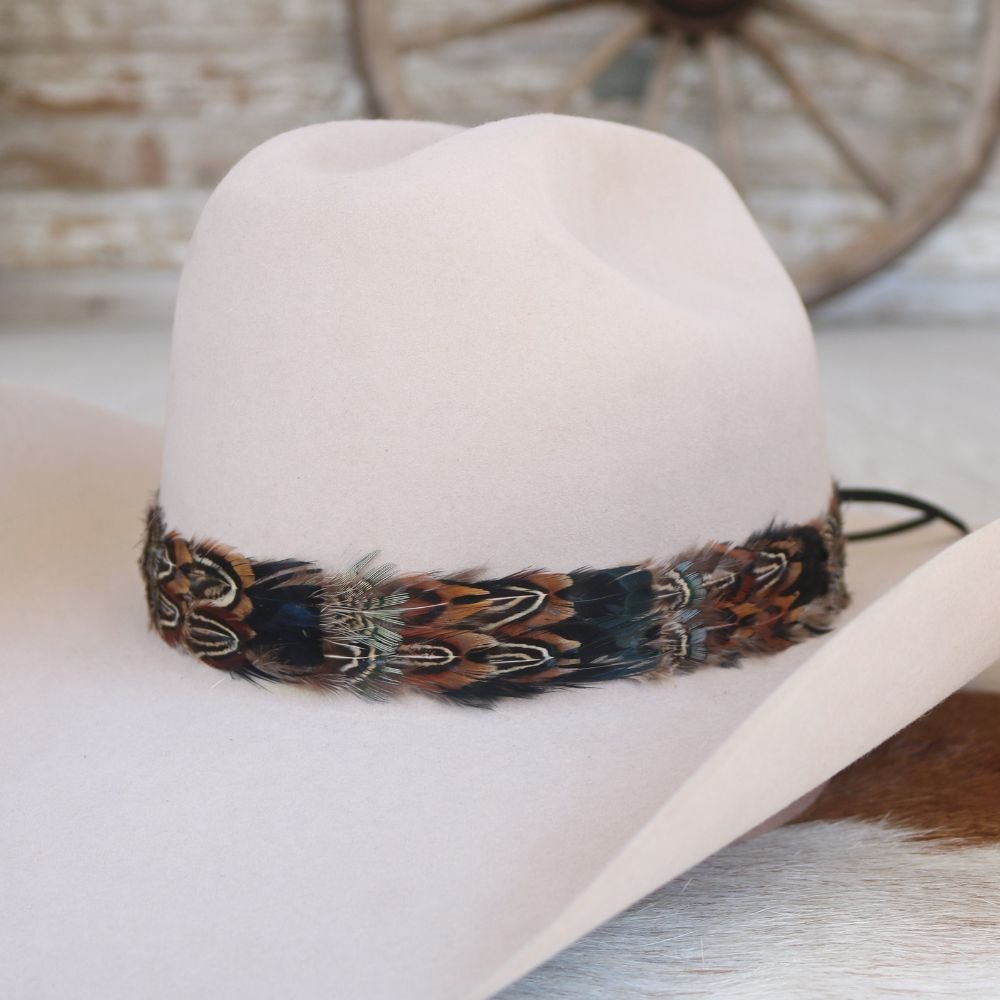 Cream cowboy hat featuring a multicolor feather band near the brim