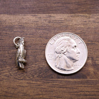 Sterling silver cockatoo charm shown beside a coin for size, bird details visible