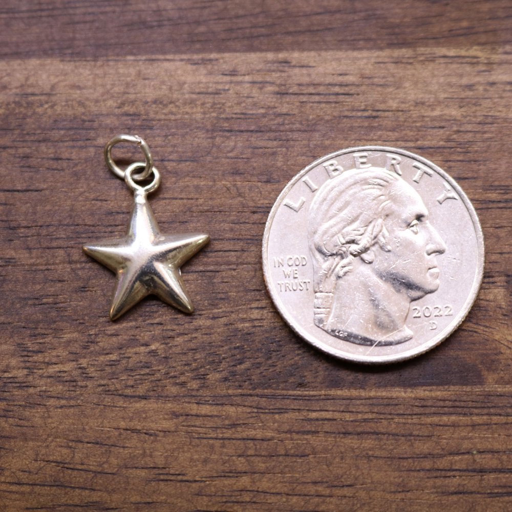Sterling silver star charm with loop bail beside a coin for size