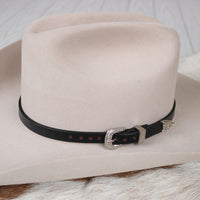 Tan cowboy hat with black leather band and metal buckle, Holt style