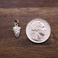 Sterling silver arrowhead charm with textured surface, sized beside a quarter
