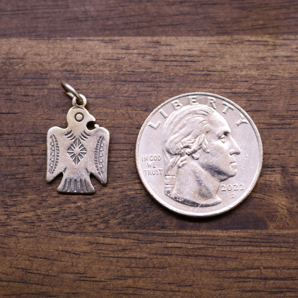 Sterling silver Thunderbird charm pendant beside a coin for size