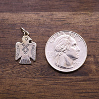 Sterling silver Thunderbird charm pendant beside a coin for size
