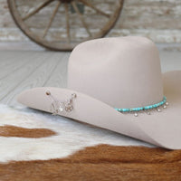 Sterling silver multi-charm necklace resting on a light cowboy hat