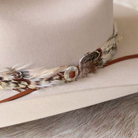 Silver slotted concho on brown leather band with feather accents