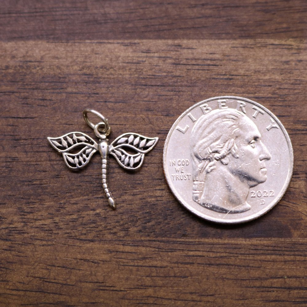 Sterling silver dragonfly charm next to a quarter for scale