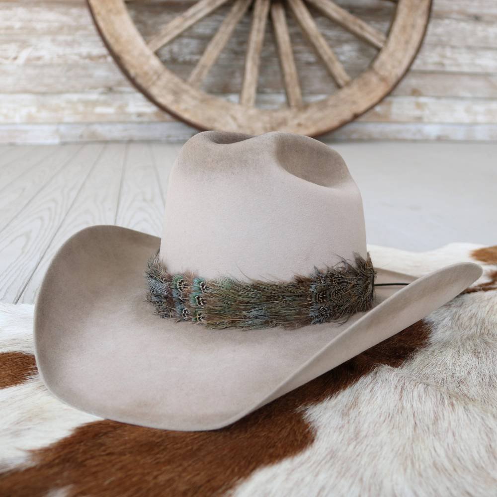 Tan cowboy hat with dark feather band and teal stitching on side