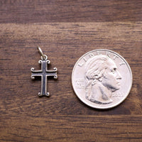 Sterling silver cross charm next to a coin for size, detailed ornate cross design