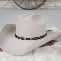 Studded goat leather hat band with gold dots on dark band across a light cowboy hat