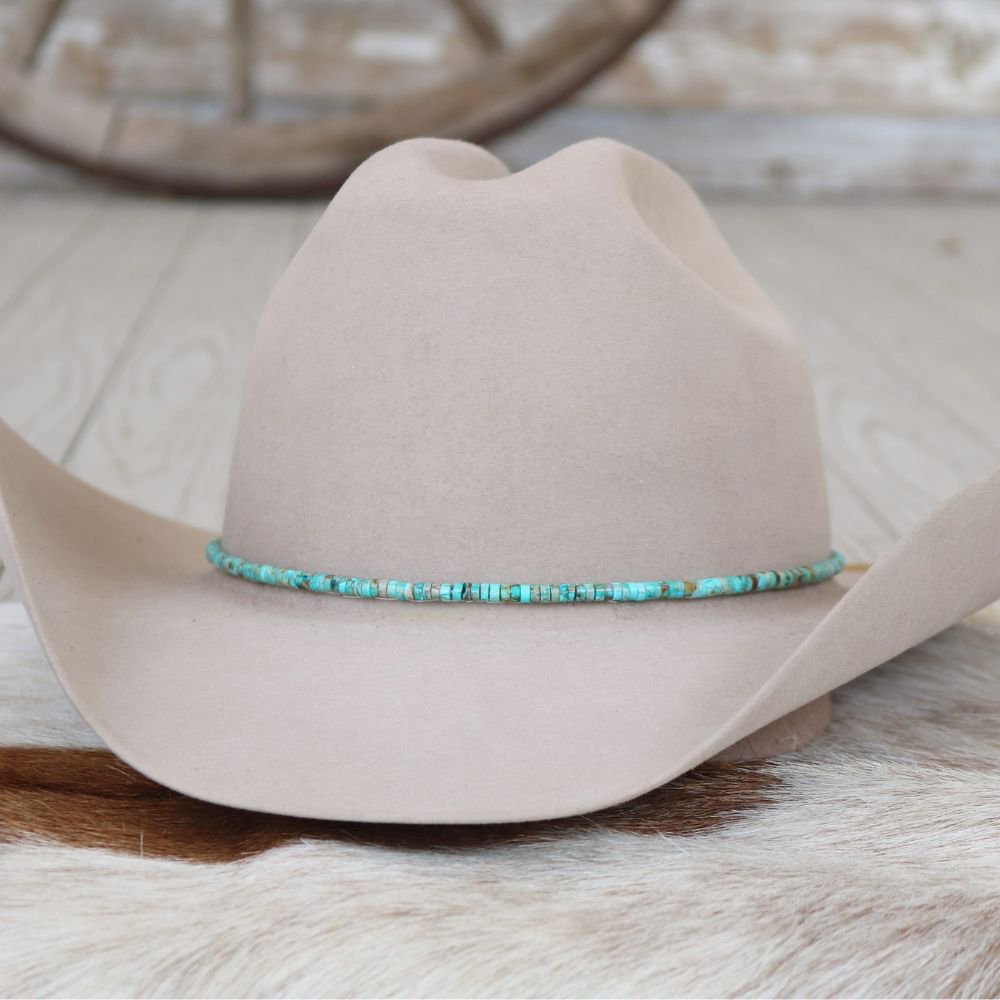Beige cowboy hat with turquoise beaded hat band around the brim