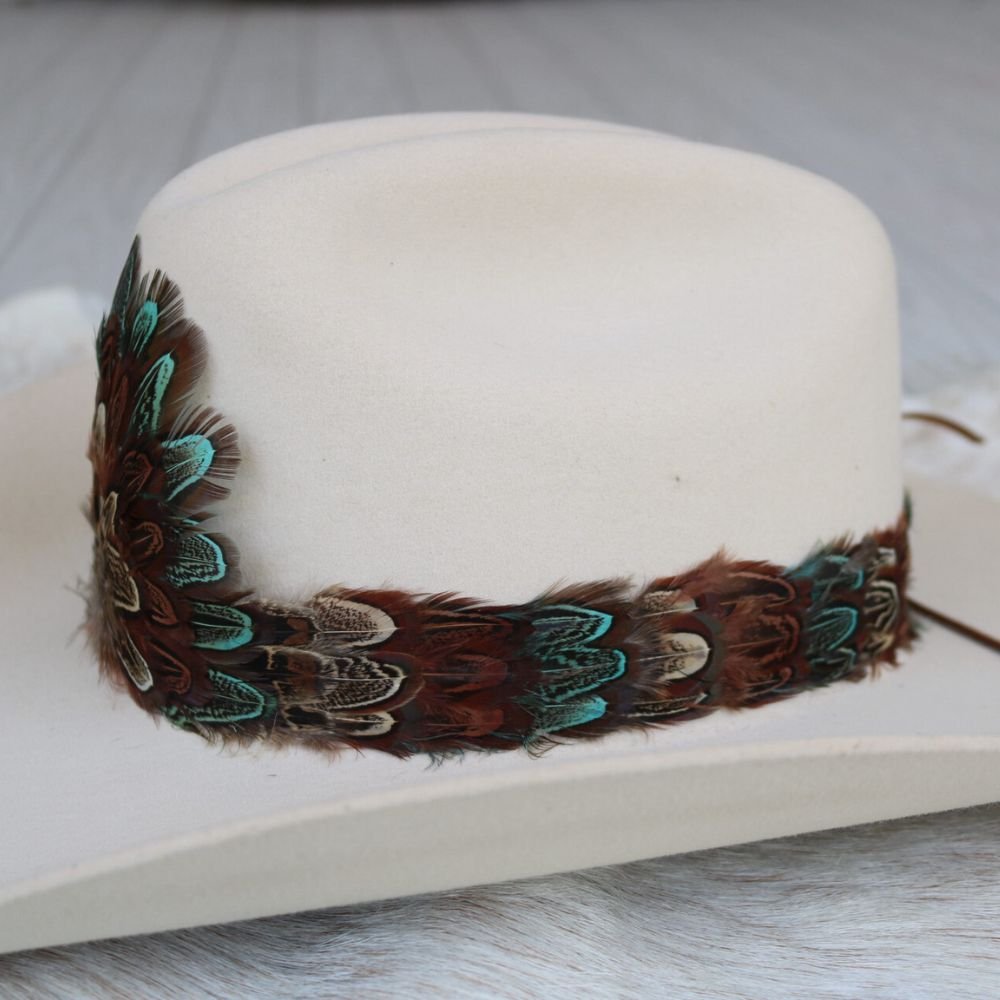 Cream felt cowboy hat with multicolor feather hat band along the front brim