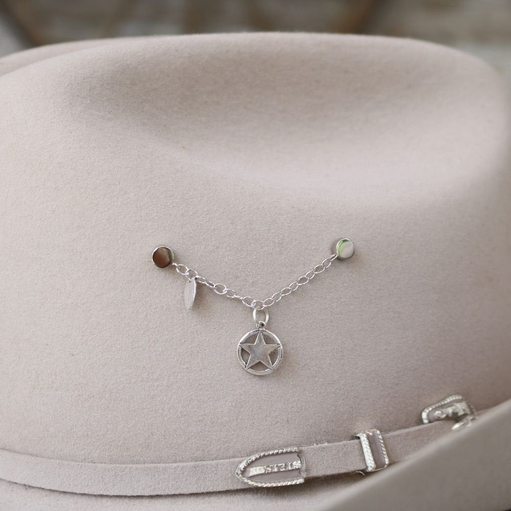 Sterling silver star charm with chain and small rings, worn on a light hat