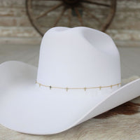 Gold-plated cross hat band chain on a white cowboy hat brim