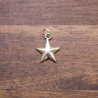 Sterling silver star charm with loop bail, hanging on a wooden surface