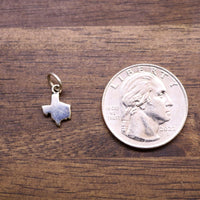 Sterling silver Texas-shaped charm next to a coin for size