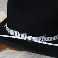 Silver slotted concho set on feather-trimmed band