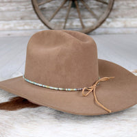 Brown felt hat with turquoise beaded hat band and tan lace tie on side