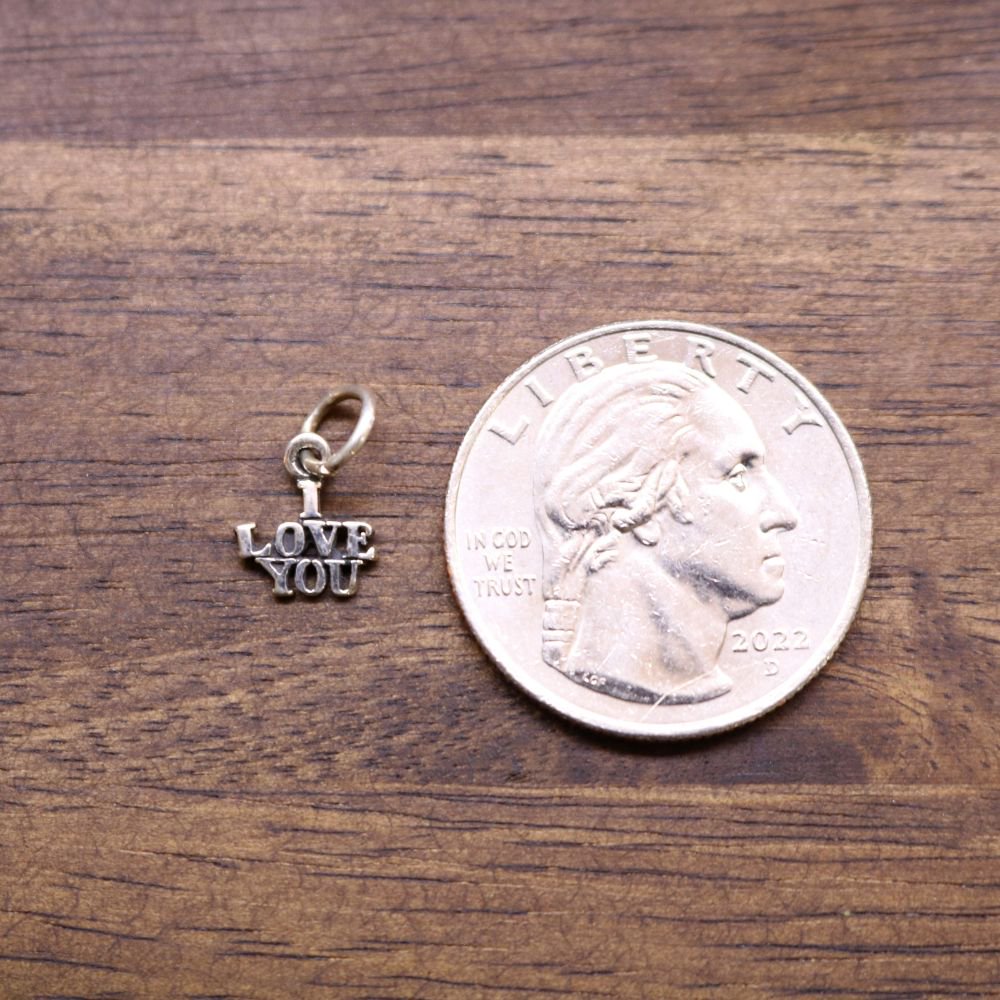 Sterling silver LOVE YOU charm beside a quarter coin for scale