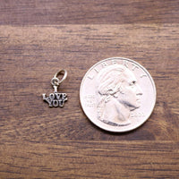 Sterling silver LOVE YOU charm beside a quarter coin for scale