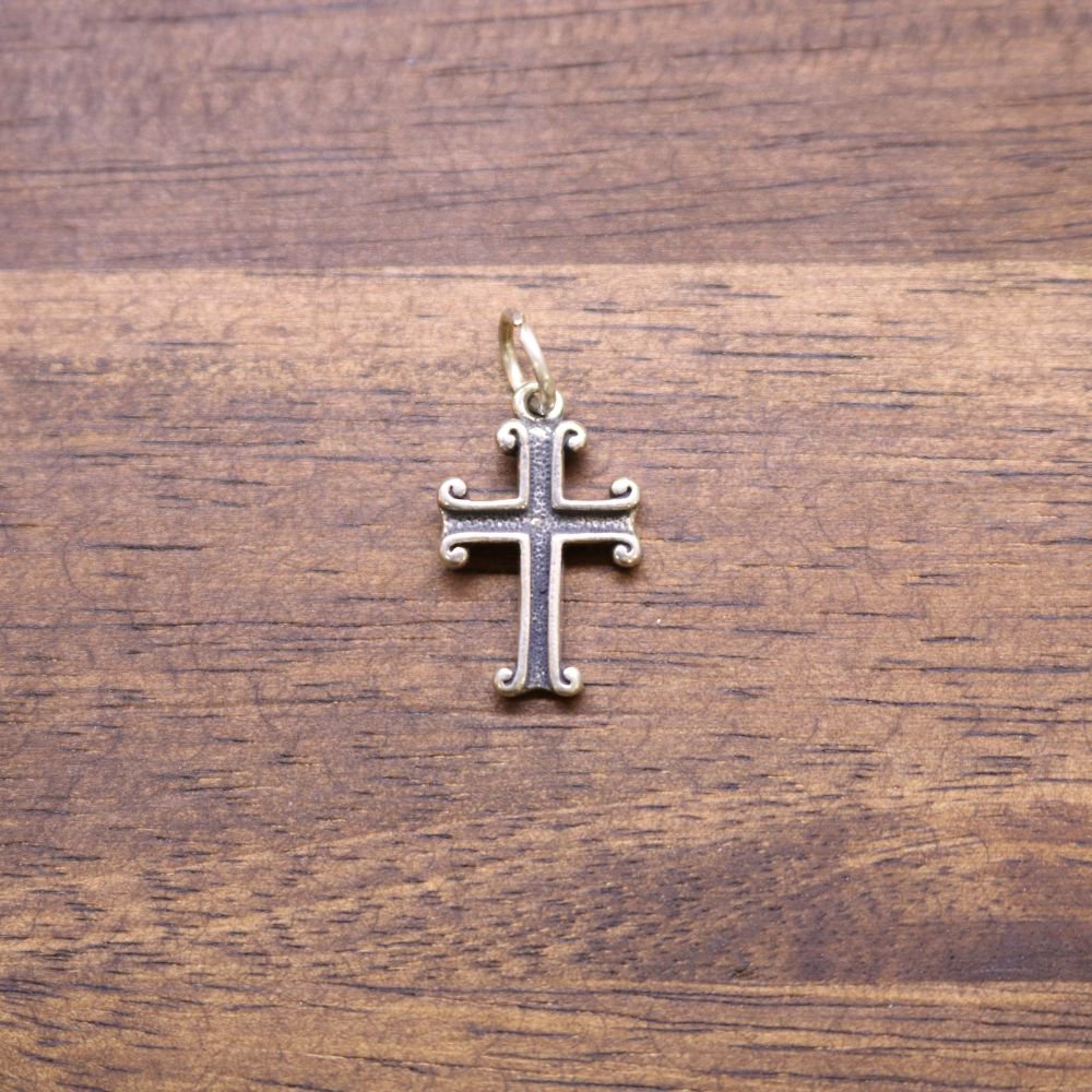 Sterling silver cross charm with small hanging loop, ornate scrollwork edges