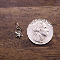 Sterling silver eagle charm pendant with loop bail, shown beside a coin